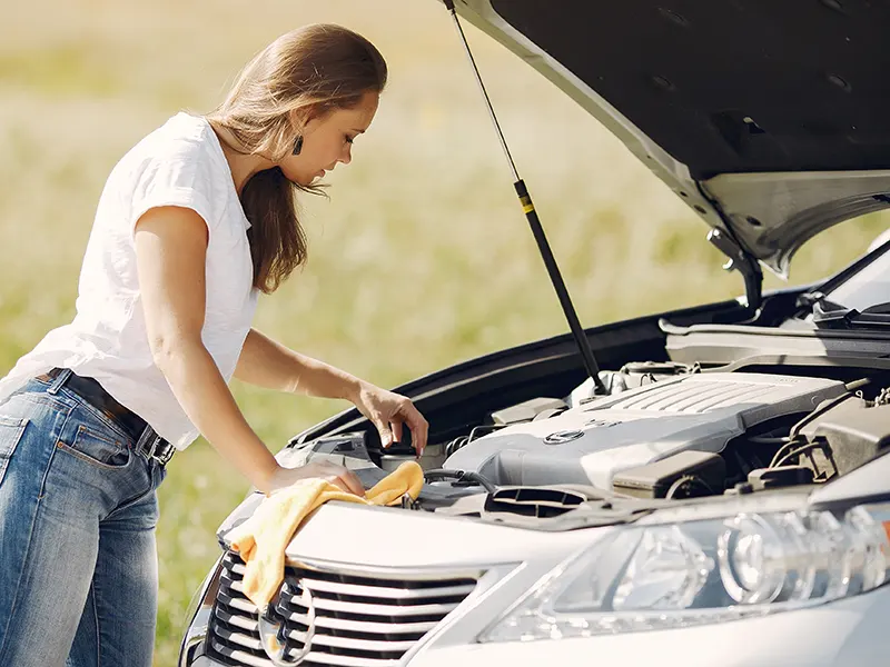 woman looking at her car engine overheating